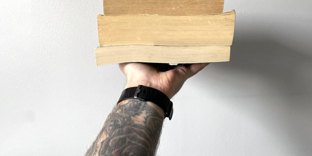 Hand holding up several books