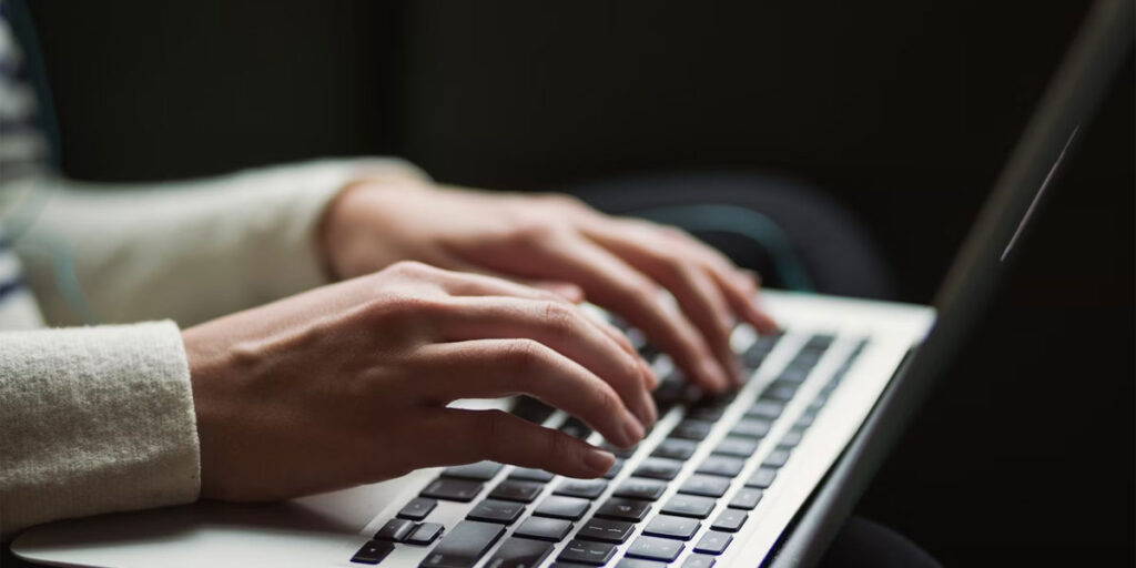 Hands typing on a laptop