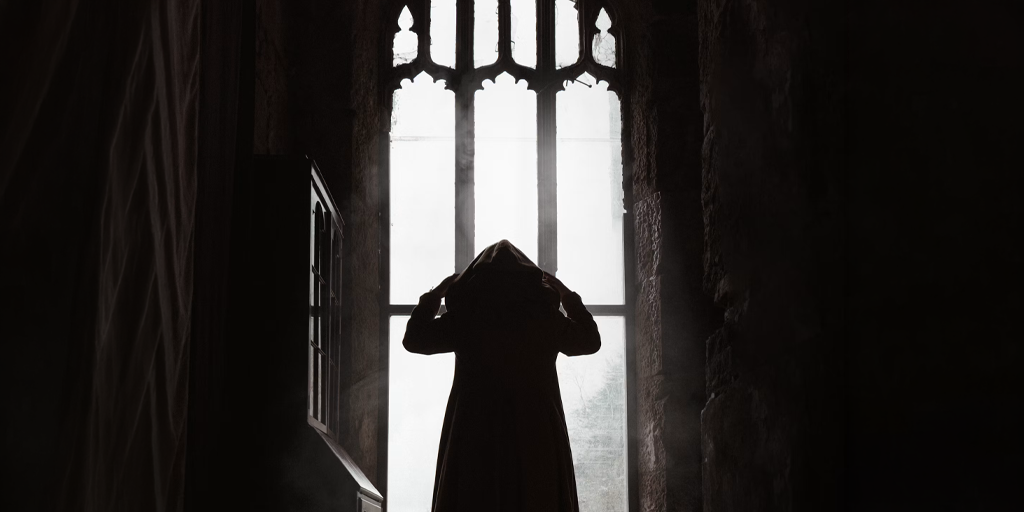 Hooded figure standing in front of a window